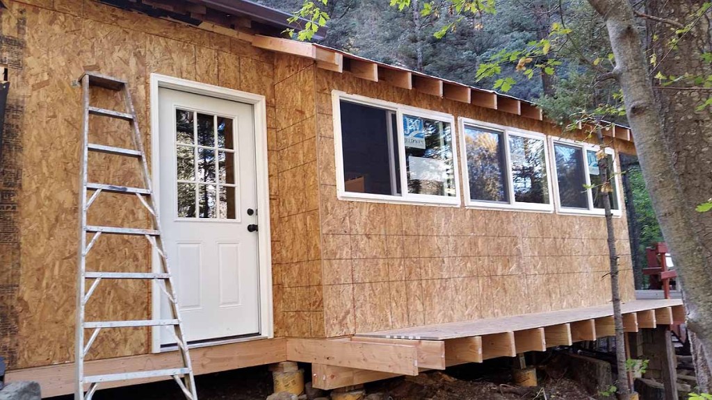 The part of the kitchen that "sticks out" is under the new roof line.   The part where the door is falls under the old "living room" roof line. The foundation of the kitchen is now very nicely supported underneath.  he windows cover about pretty much the entire length of the "stream" wall and all can be opened for ventilation and sound. Both exterior doors have nice windows also.